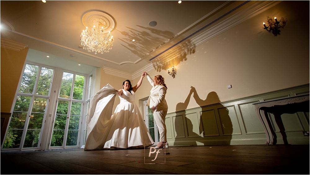 South Wales Wedding Bliss: Newlyweds dancing joyfully in the beautifully lit Bryngarw House ballroom.